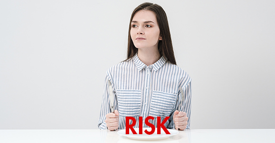 Hungry thin girl sitting at the table in front of an empty plate with a knife and fork. (Demo)