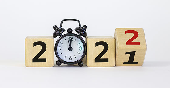 Business concept of 2022 new year Turned a wooden cube and changed number 2021 to 2022 Black alarm clock Beautiful white background copy space 2022 new year concept Demo