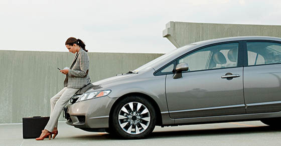 Businesswoman texting on mobile phone in car park Demo